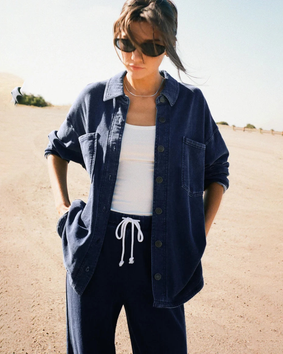 Woman wearing a blue denim button down jacket  with drawstring pants in the desert