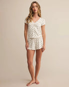 woman wearing white pajama top and shorts with a subtle rose pattern