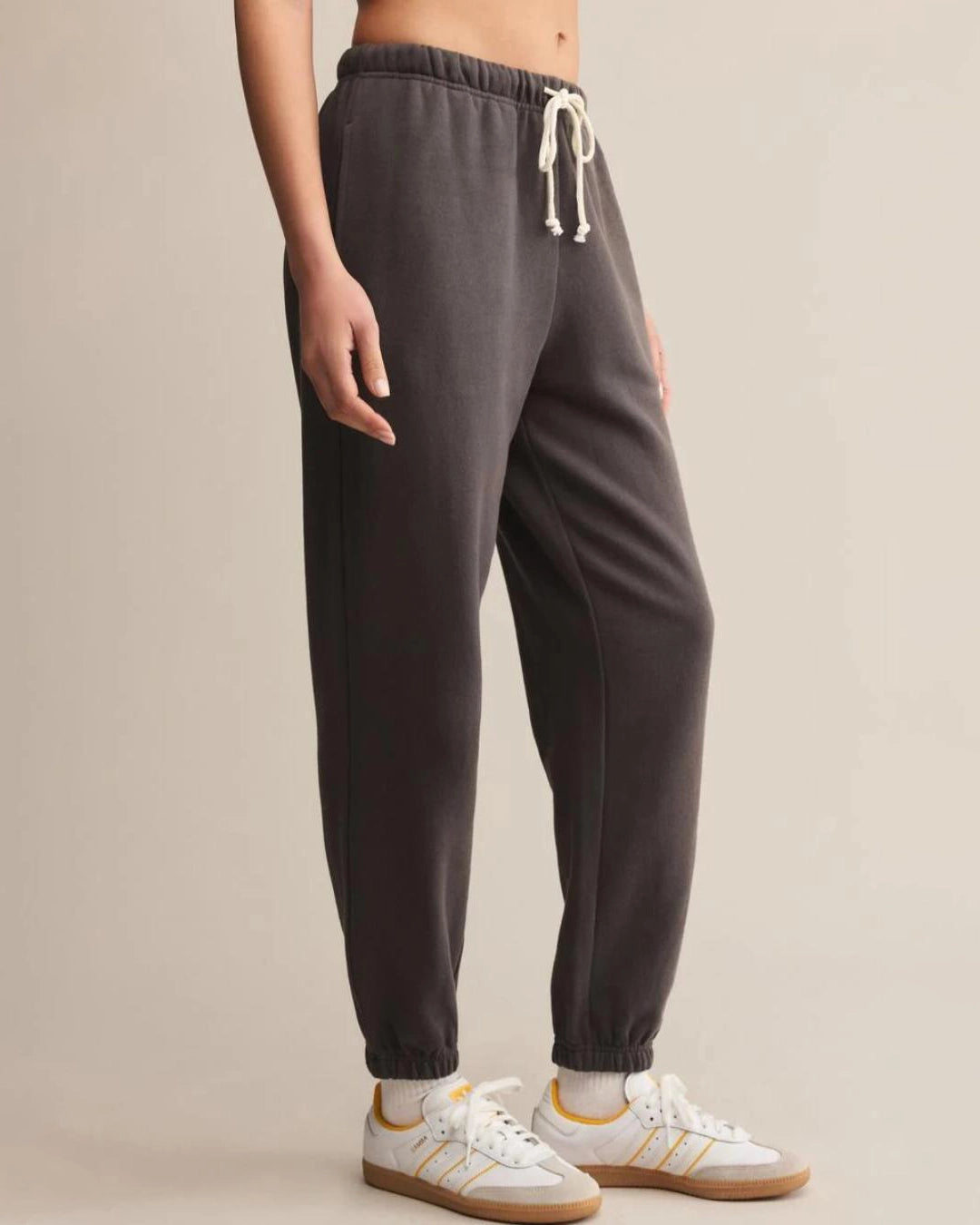a woman wears dark gray cotton sweatpants with cream drawstring