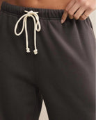 a woman wears dark gray cotton sweatpants with cream drawstring