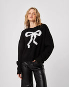 Woman wearing a black fluffy sweater with a white bow design