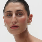 large square gold earrings with white stone in the middle