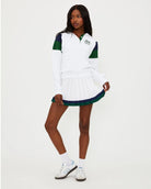 Woman wearing a white tennis top with green and navy accents