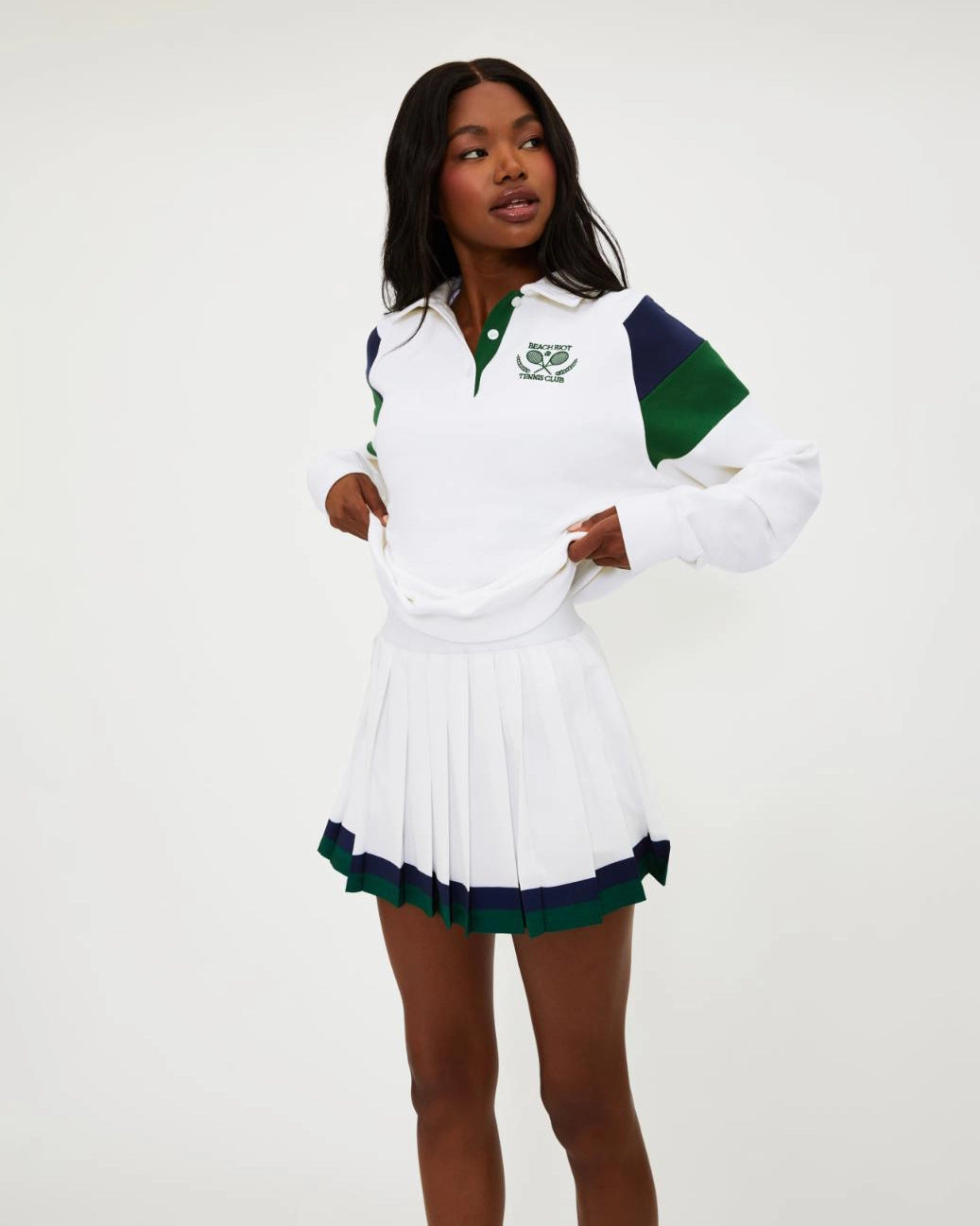 Woman wearing a white tennis top with green and navy accents