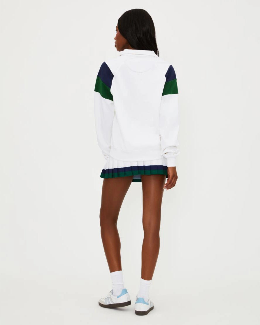 Woman wearing a white tennis top with green and navy accents