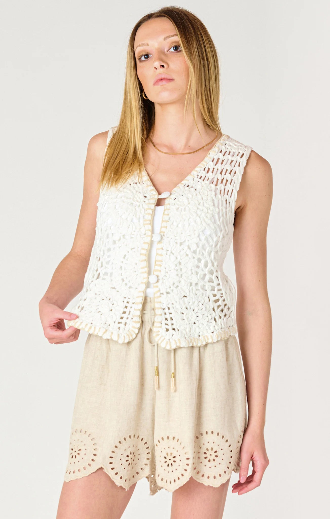 a crochet off white vest that does up in the front with buttons