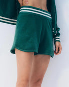 A woman wearing green cashmere varsity styleshorts and a matching top with white stripes
