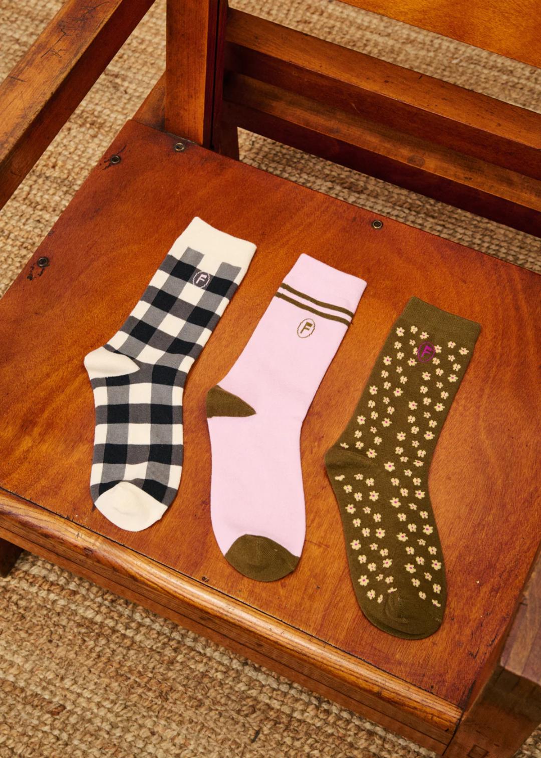 Three pairs of socks on a wooden chair with a textured carpet background