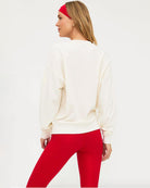 Woman wearing a white sweatshirt with 'FA LA LA LA' text and red leggings on