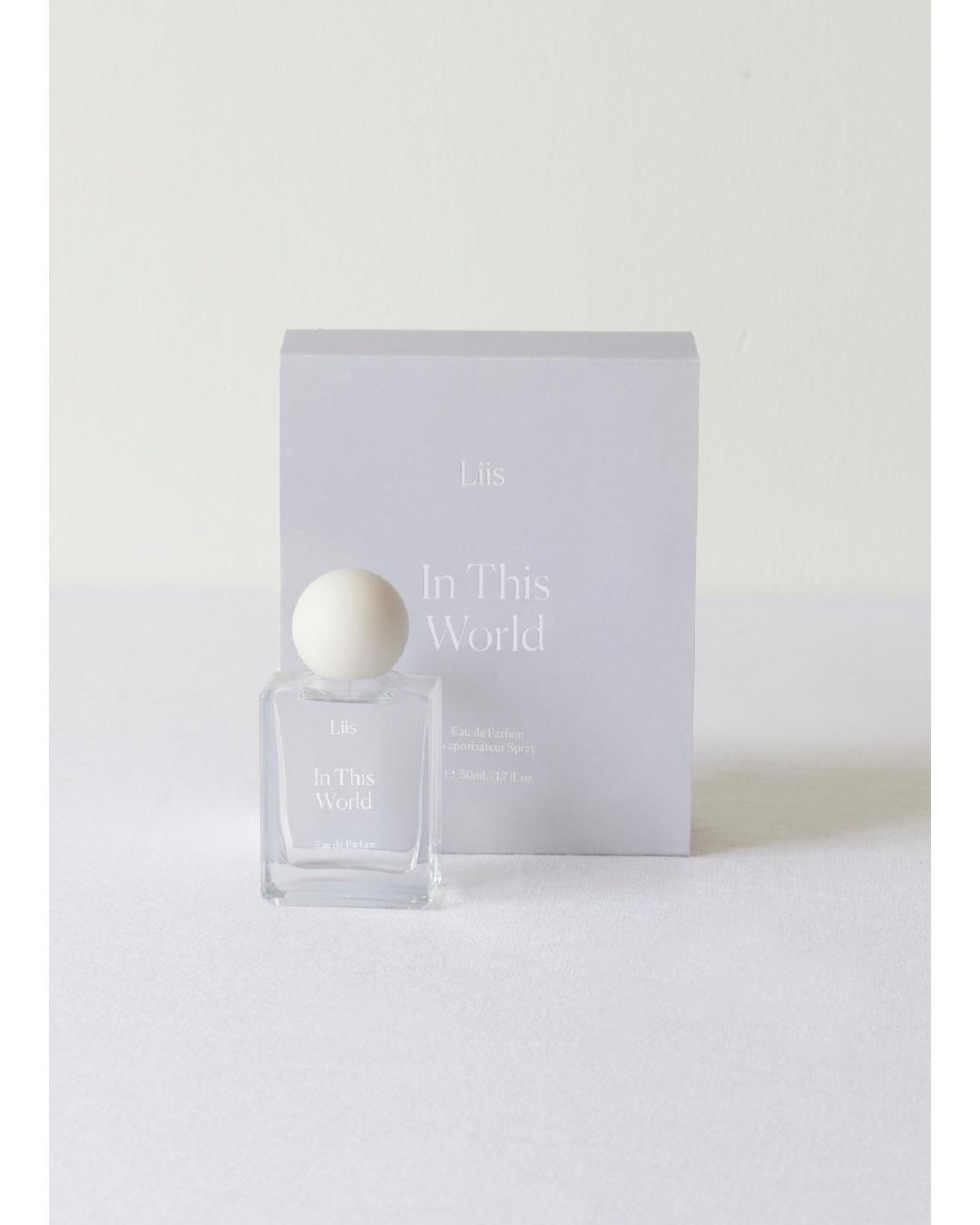 Perfume bottle and packaging with 'In This World' branding on a white background