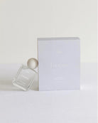 White perfume bottle with a white cap on a white background that says 'Lucienne' on it
