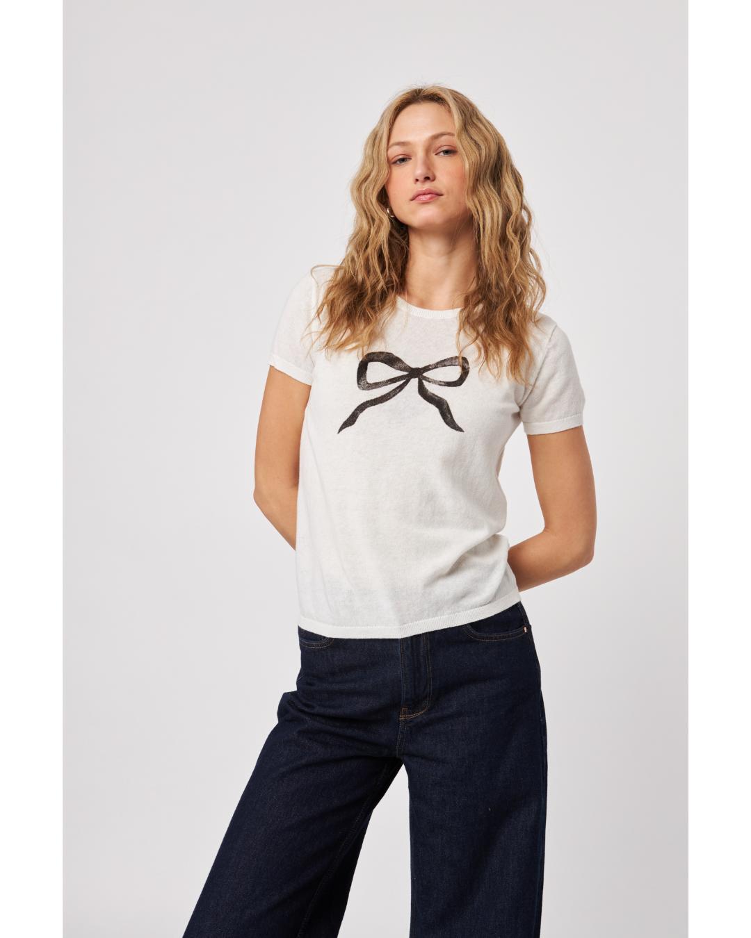 white knit top with a black bow on the front