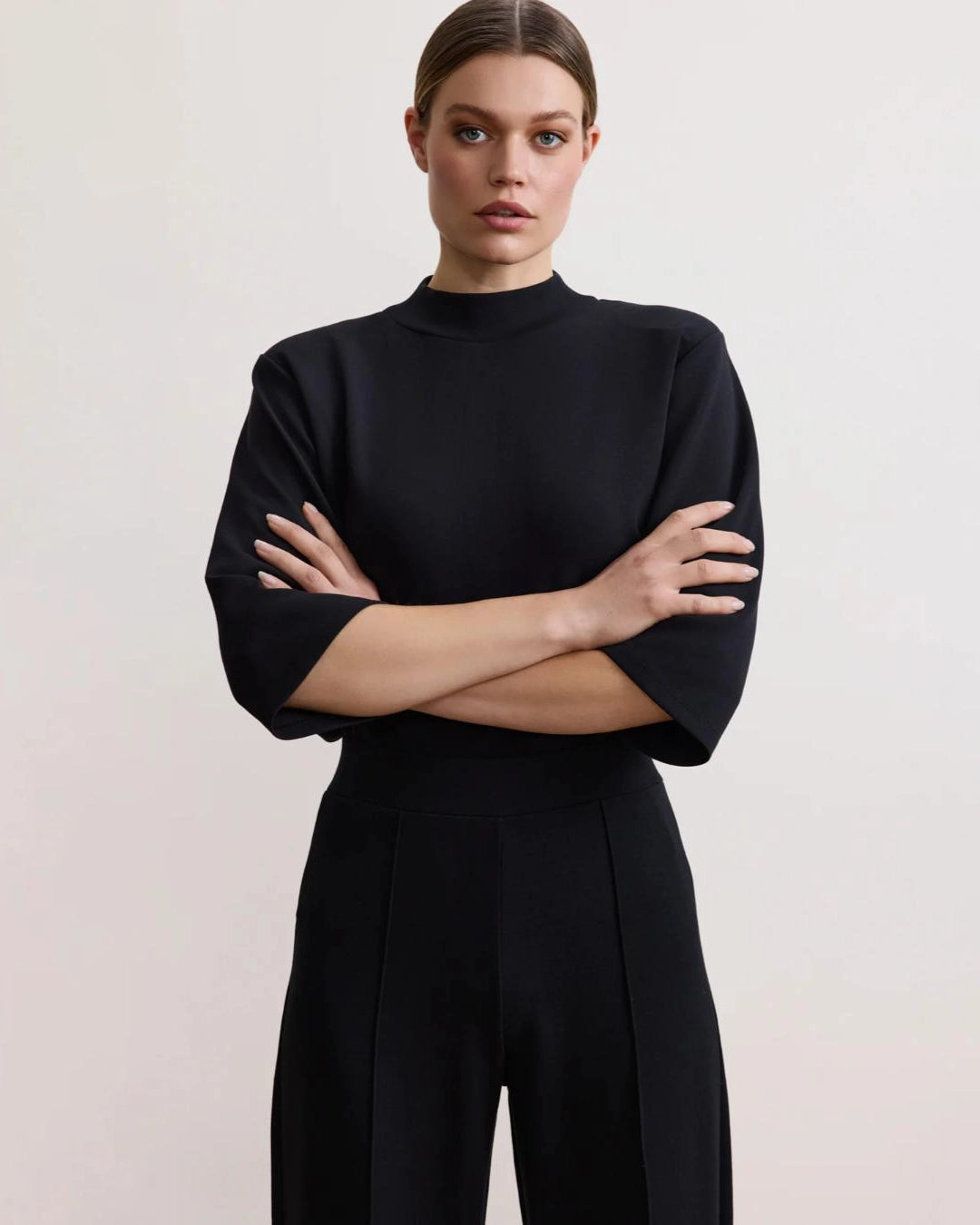 Woman wearing a black bracelet sleeve top with mock neck