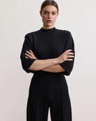 Woman wearing a black bracelet sleeve top with mock neck