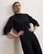 Woman wearing a black bracelet sleeve top with mock neck