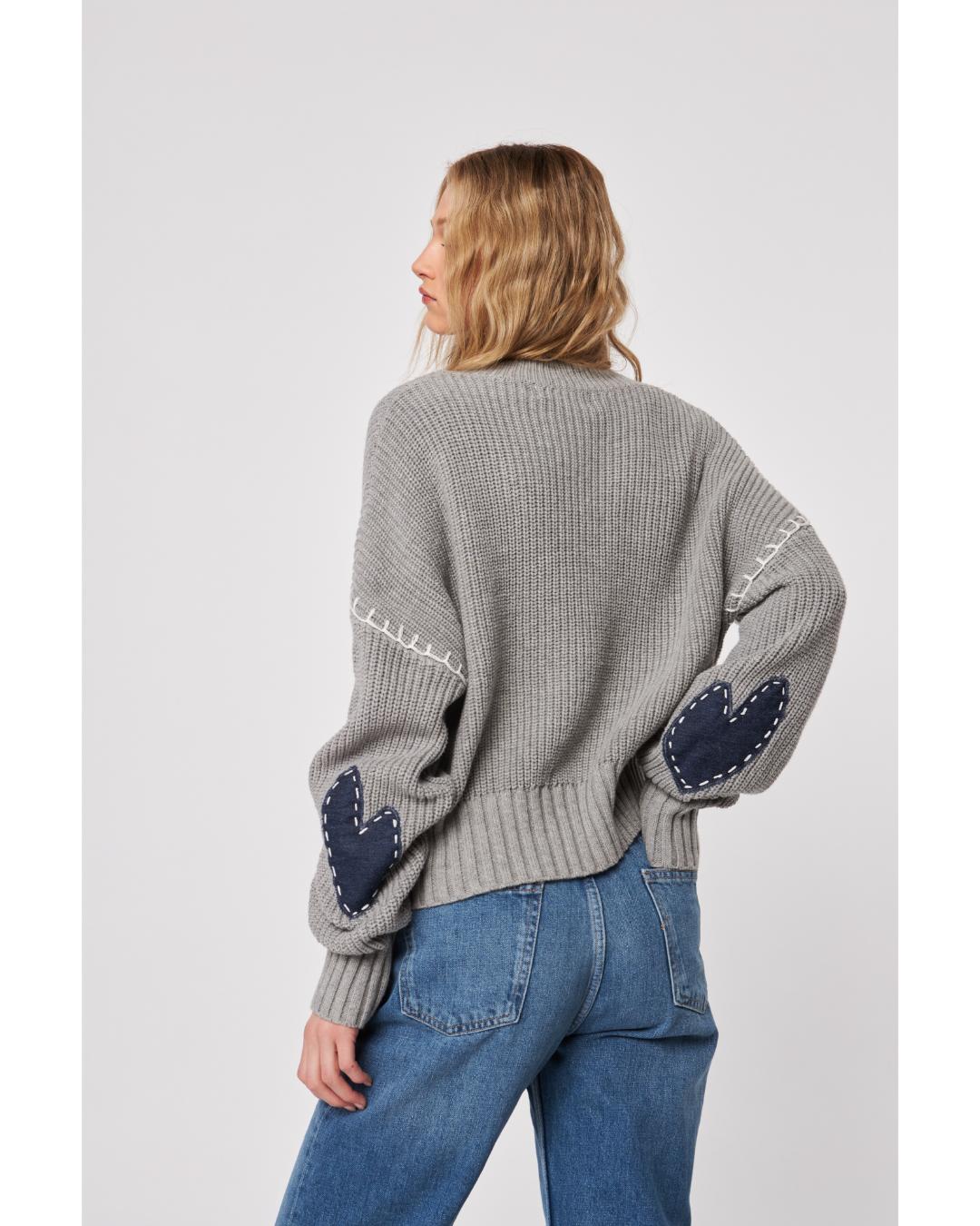 Woman wearing a gray sweater with 'LOVE' printed on it 