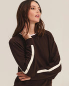 Woman wearing a brown sweatshirt with white stripes and matching pants