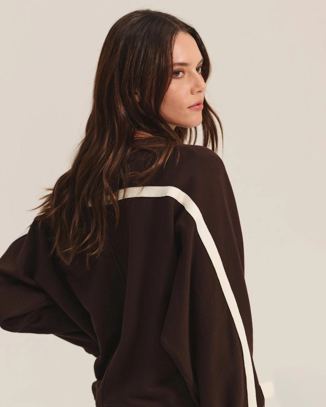 Woman wearing a brown sweatshirt with white stripes and matching pants