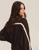 Woman wearing a brown sweatshirt with white stripes and matching pants