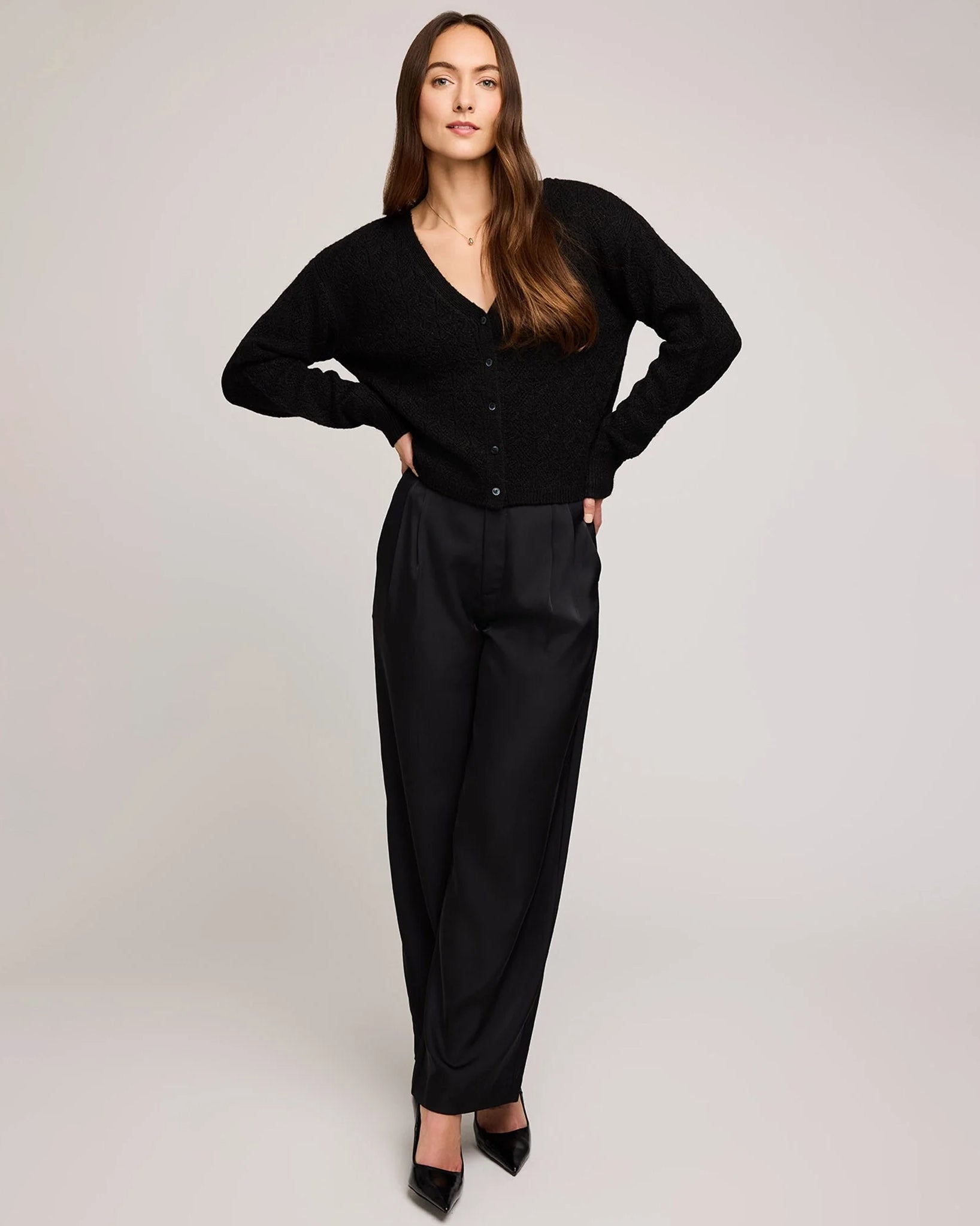 a woman wears a pointelle v neck button down cardigan in black by gentle fawn