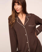 Woman wearing a chocolate brown set of modal pajamas with ivory piping by Eberjey