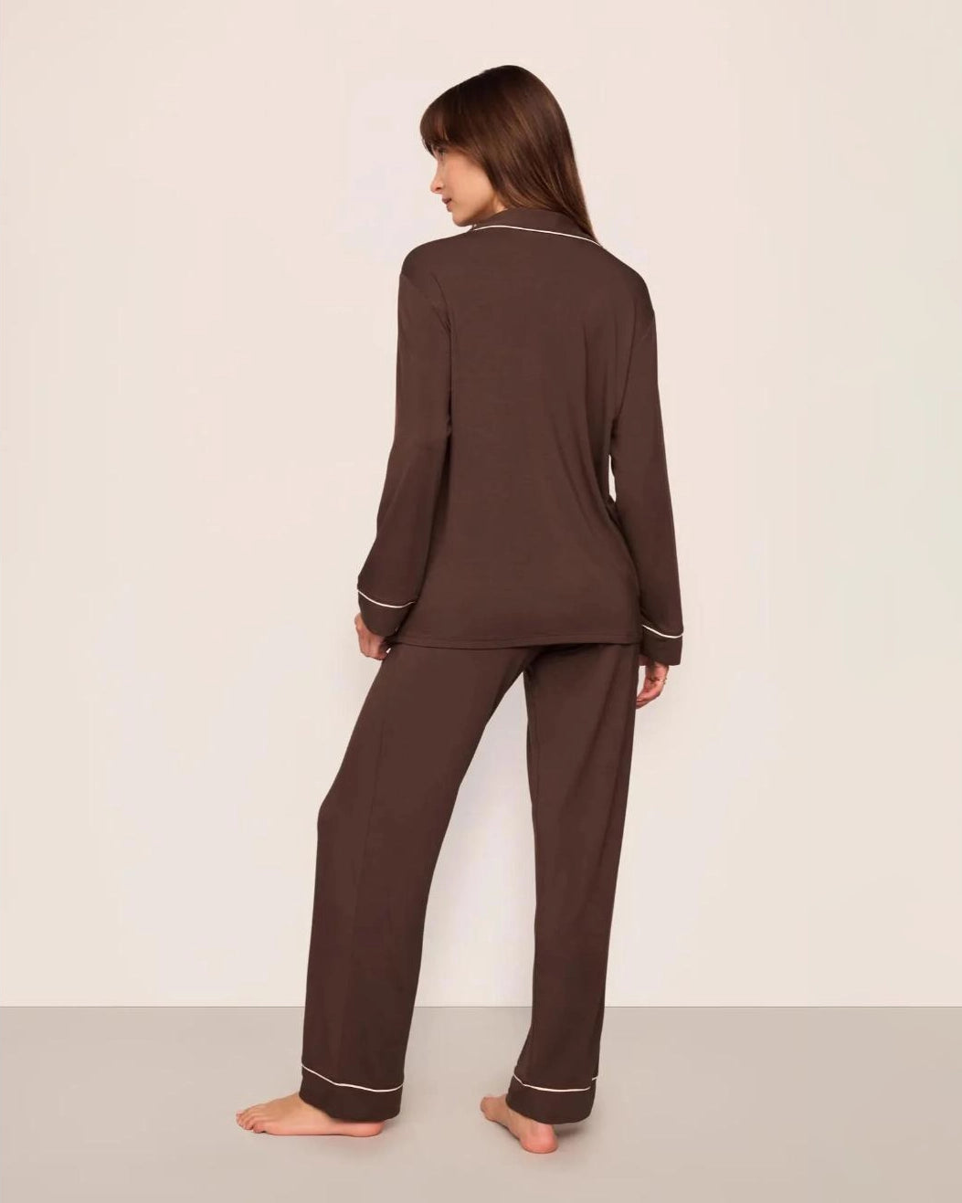 Woman wearing a chocolate brown set of modal pajamas with ivory piping by Eberjey