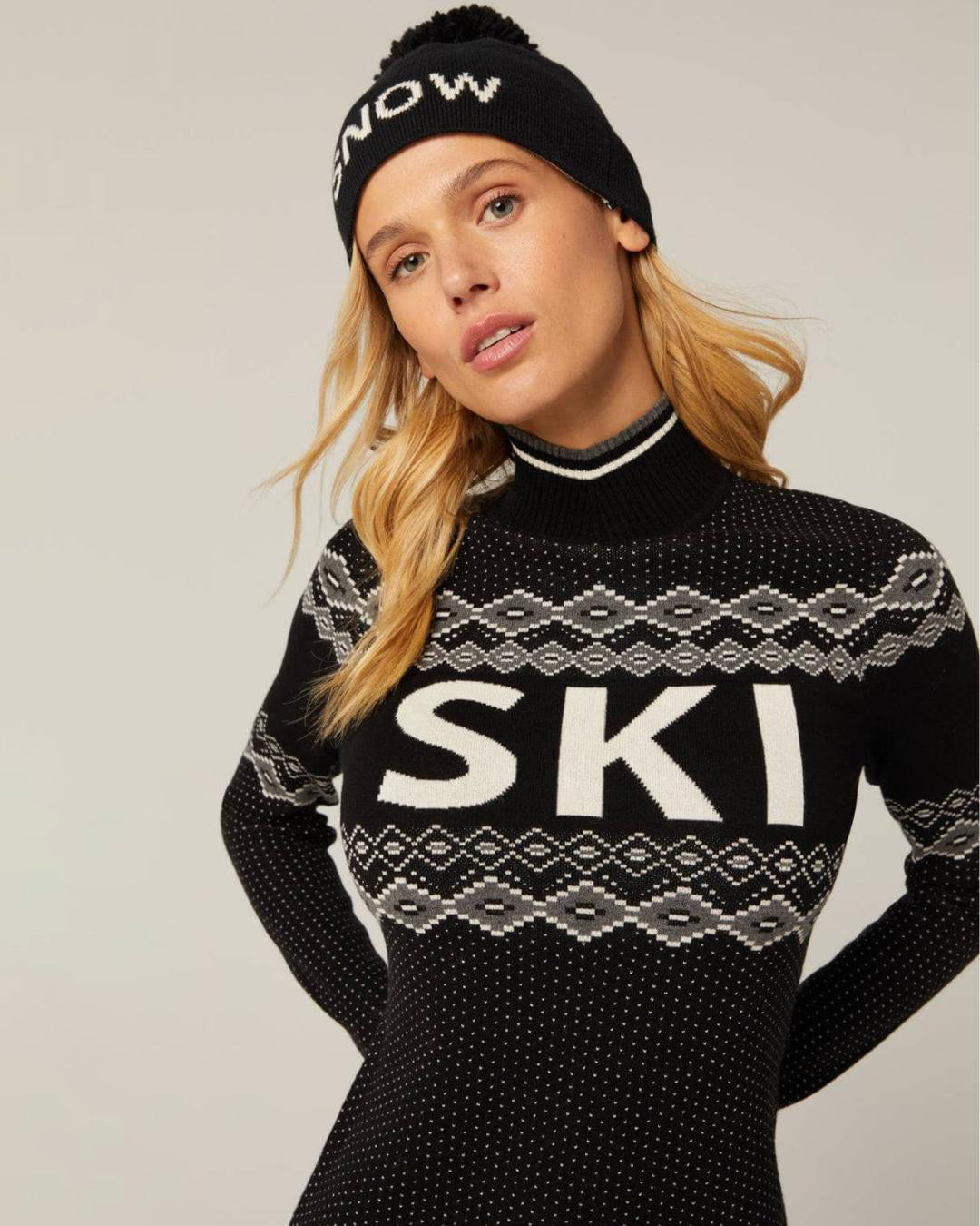 Woman wearing a black knit sweater with 'SKI' text and white accents