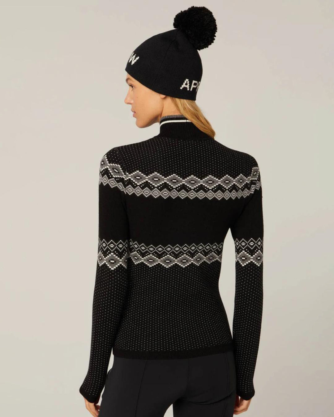 Woman wearing a black knit sweater with 'SKI' text and white accents