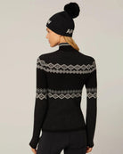 Woman wearing a black knit sweater with 'SKI' text and white accents