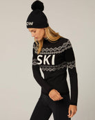 Woman wearing a black knit sweater with 'SKI' text and white accents