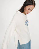 white oversized knit sweater with the text la dolce vita in blue