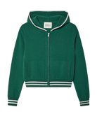 A woman wears a green varsity tracksuit style zip up hoodie with white stripes and matching shorts