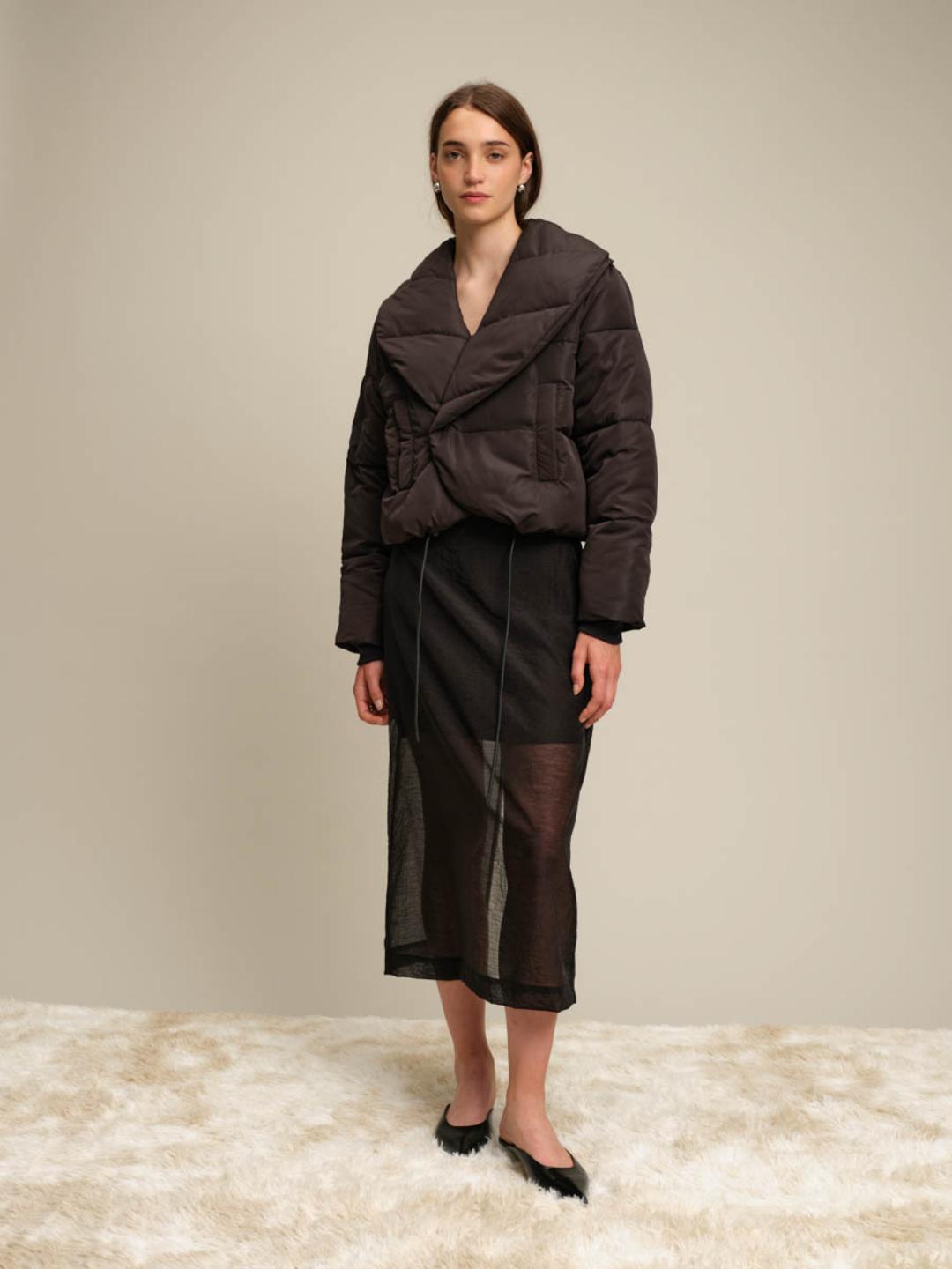 Woman wearing a black jacket and skirt on a plain background