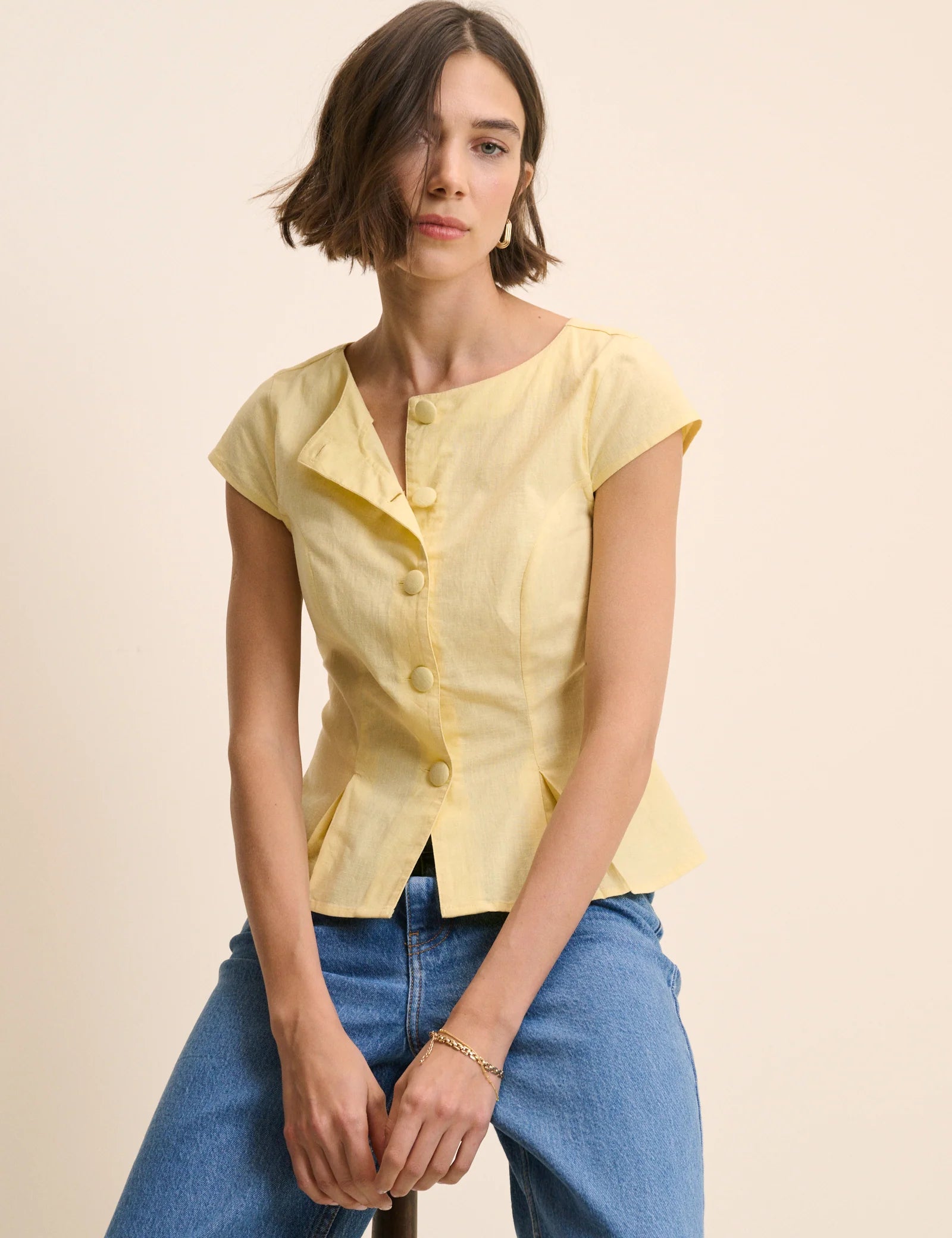 yellow top with buttons down the front and a cap sleeve