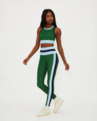 A woman wears a green racerback crop tank with light blue and navy on the bottom and sides