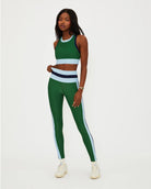 A woman wears a green racerback crop tank with light blue and navy on the bottom and sides