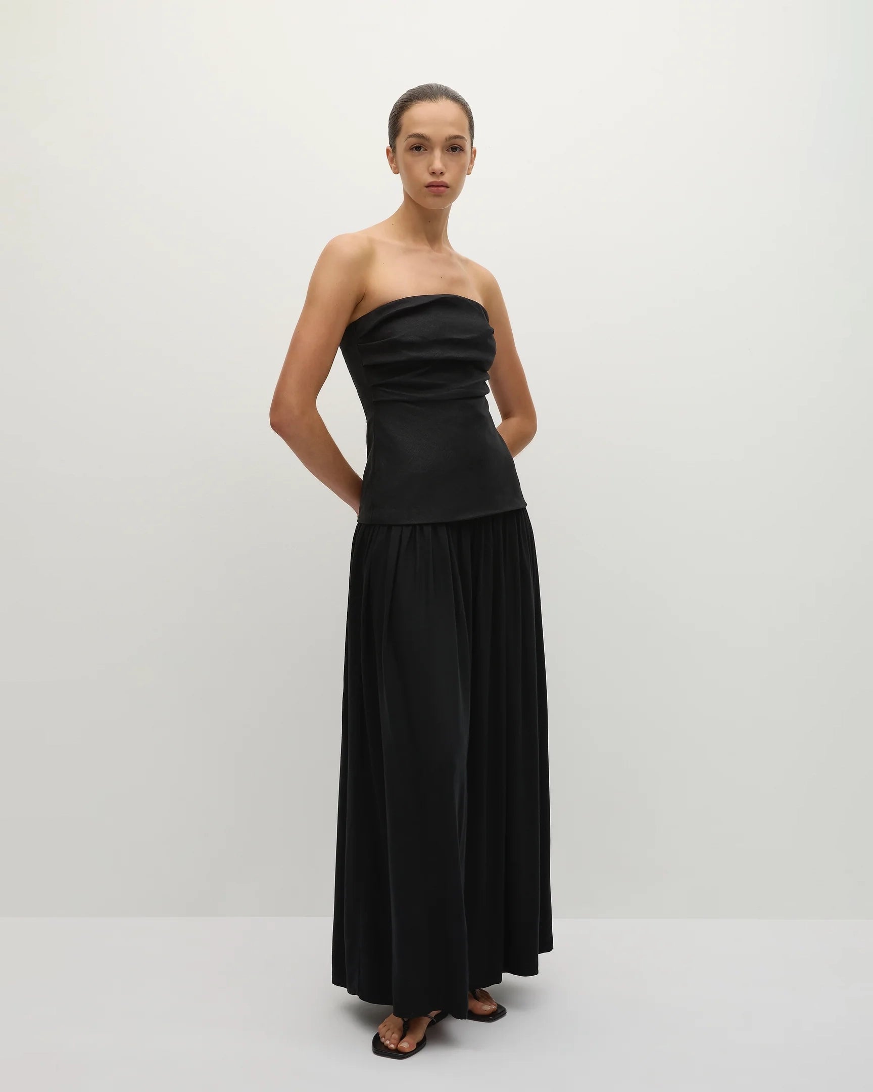 Woman wearing a long black strapless gown 