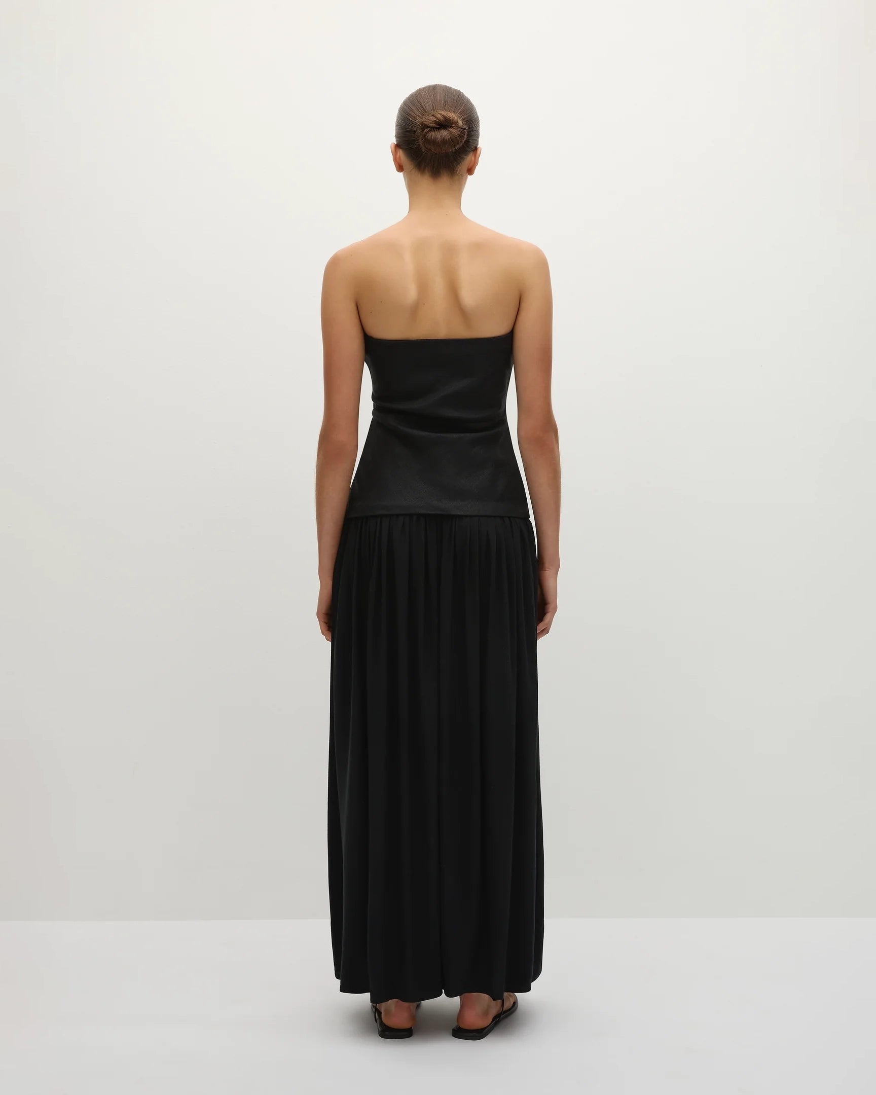 Woman wearing a long black strapless gown 