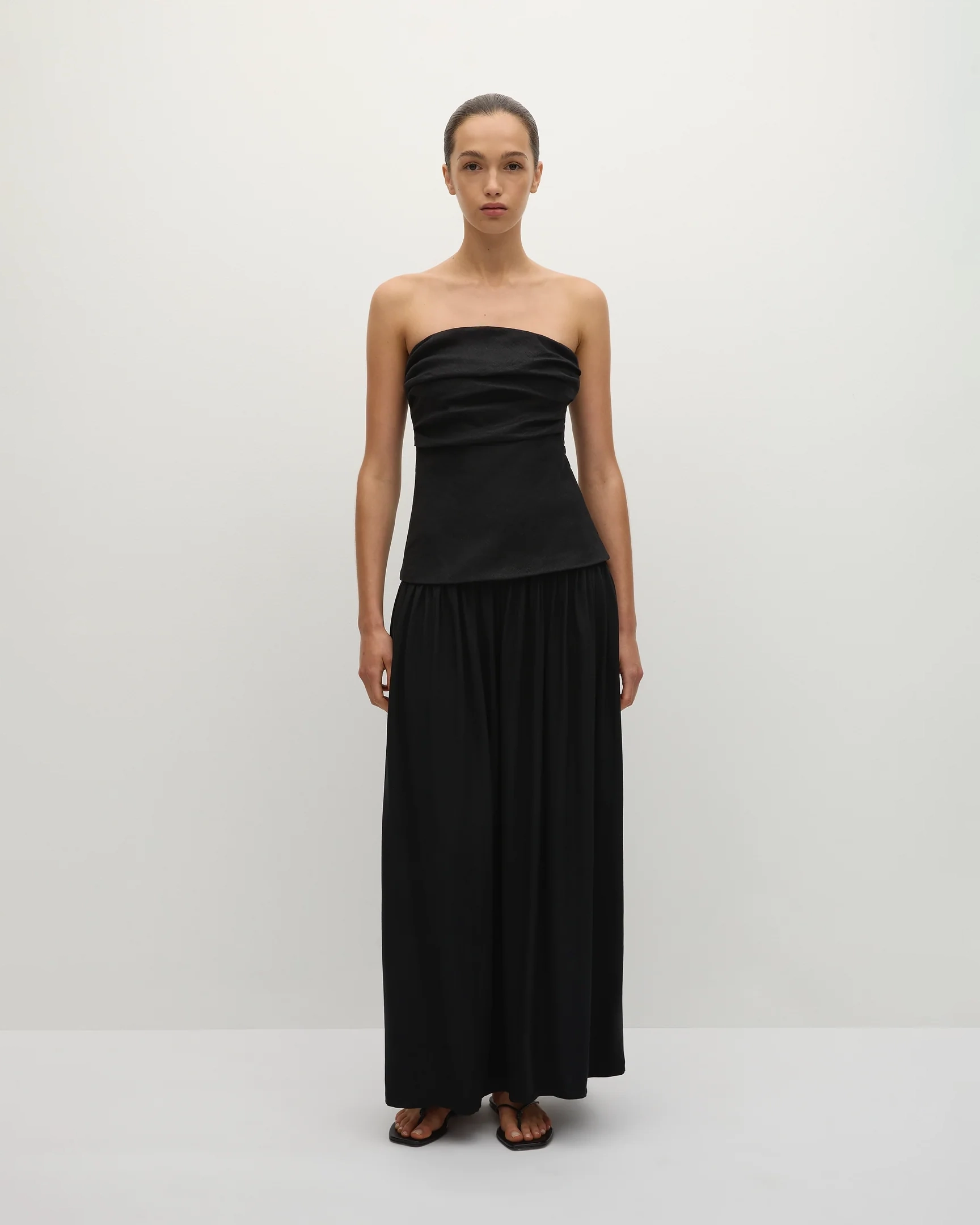 Woman wearing a long black strapless gown 