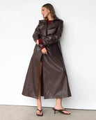 Woman wearing a long brown leather coat 