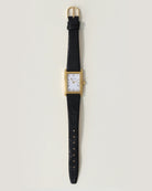 wrist watch with a black leather strap and gold and white face
