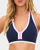 a woman wears a navy racerback sports bra with pink and white outline