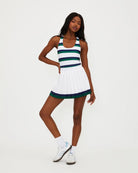 A woman wears a white pleated tennis skirt with navy and green stripe around the bottom