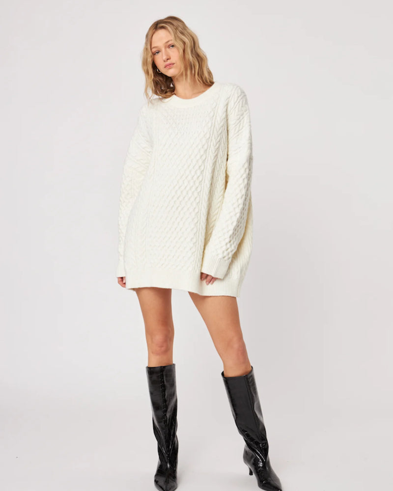 woman wearing a cable knit oversized sweater in cream with high leather boots