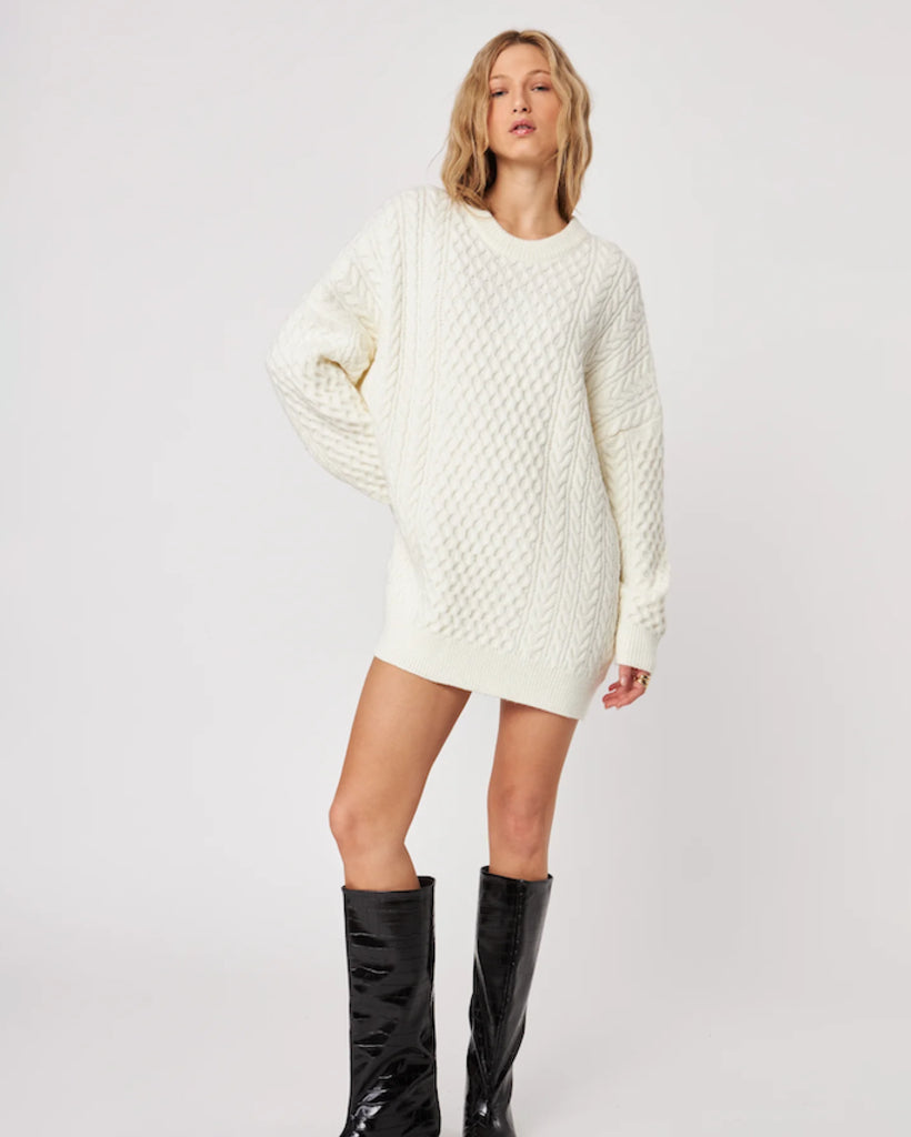 woman wearing a cable knit oversized sweater in cream with high leather boots