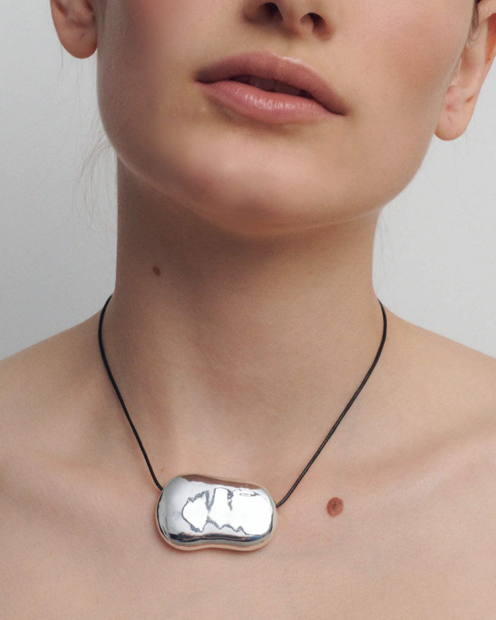 black rope necklace with statement solver pendent