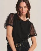 Woman wearing a black top with sheer puff sleeves