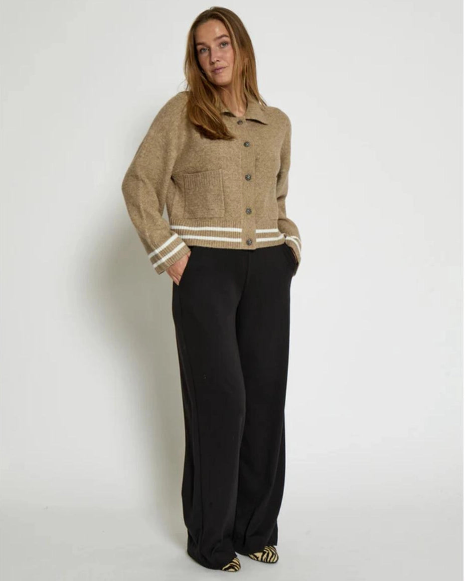 Woman wearing a beige knitted button down jacket with white trim