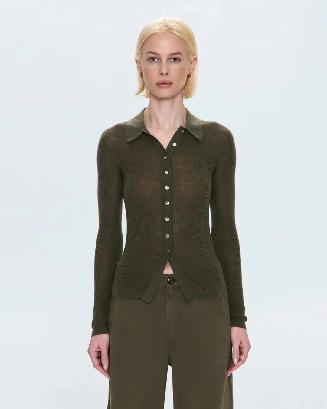 woman wearing a ribbed long sleeve top with a collar and buttons down the front in green