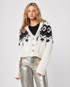 Woman wearing a patterned fairisle button down knit cardigan and silver pants
